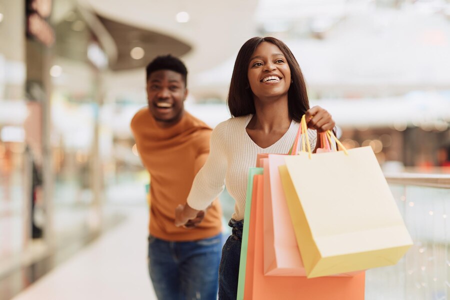 excited-black-woman-pulling-boyfriend-shopping-store_116547-16410